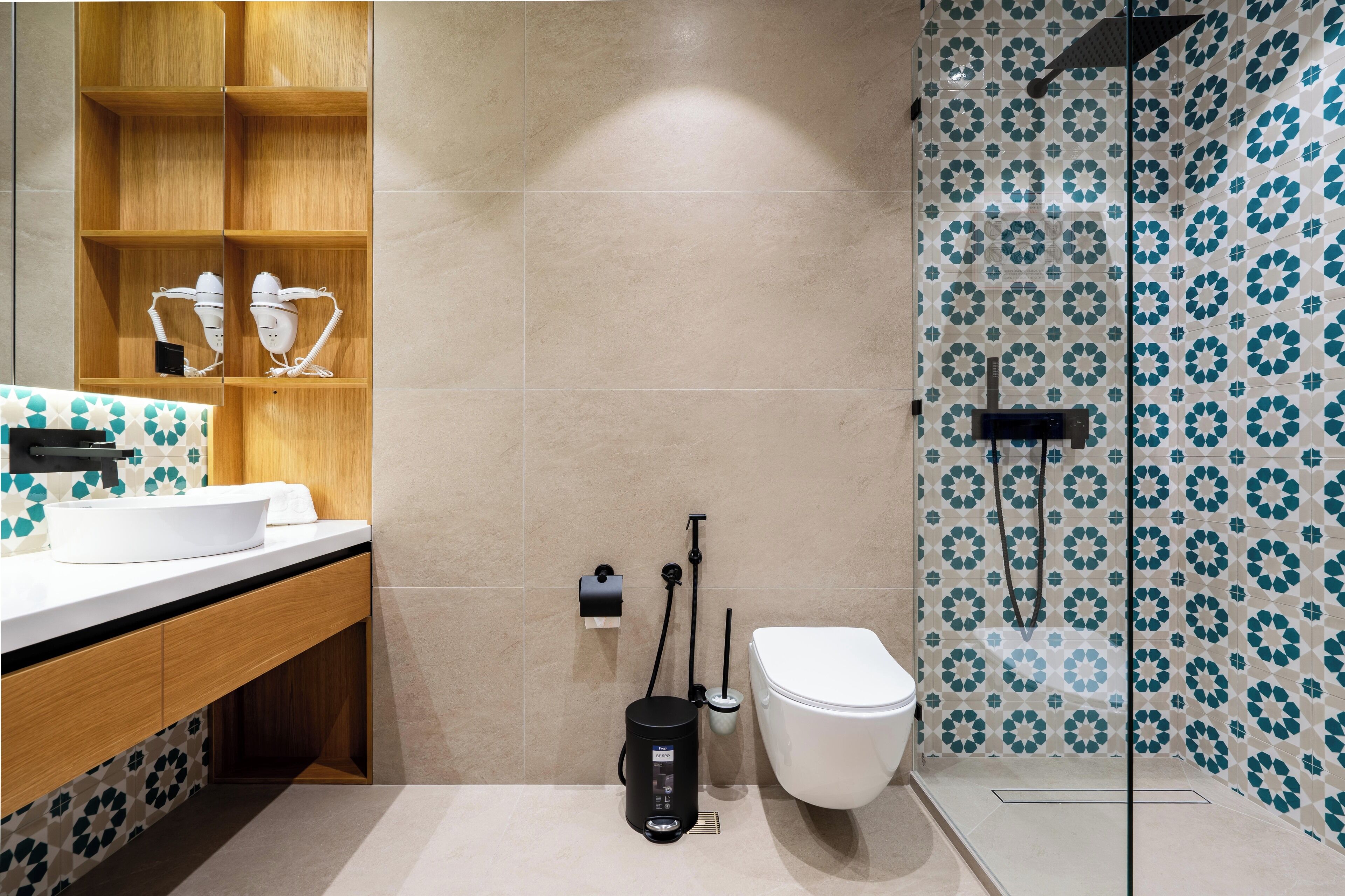 Een moderne badkamer met een witte wastafel, een houten wastafelmeubel en een douche met betegeling.