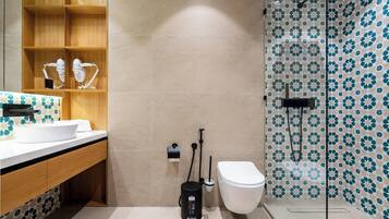 Une salle de bain moderne avec un lavabo blanc, un meuble-lavabo en bois et une douche aux carreaux décorés.