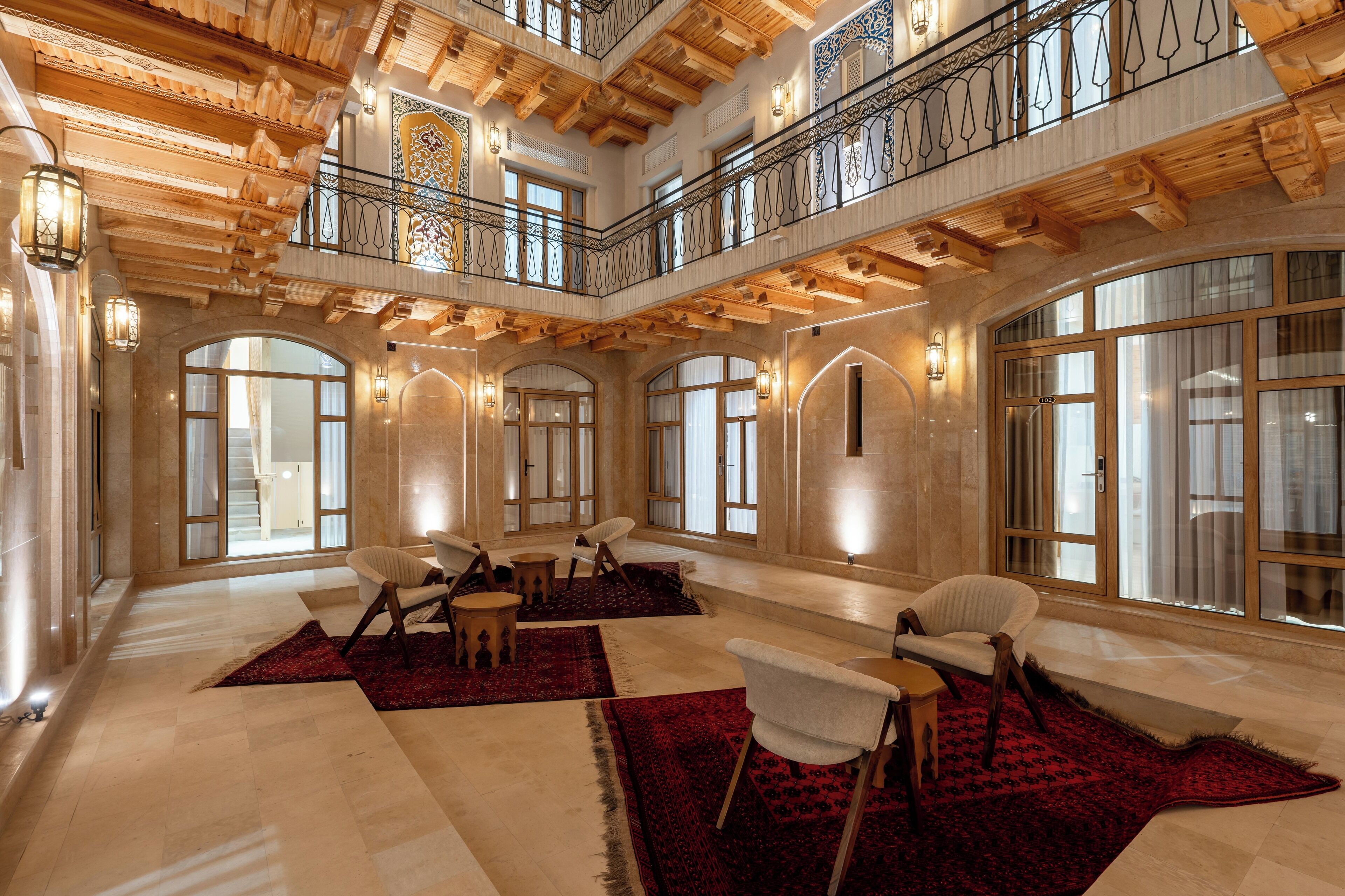 A spacious lobby with high ceilings, wooden beams, and large windows. There are several seating areas with chairs and tables.