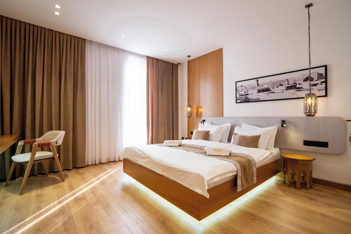 A modern hotel room with a large bed, a desk, and a chair.