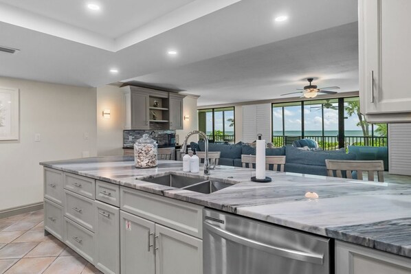 A modern kitchen with a large island, built-in appliances, and a view of the ocean.