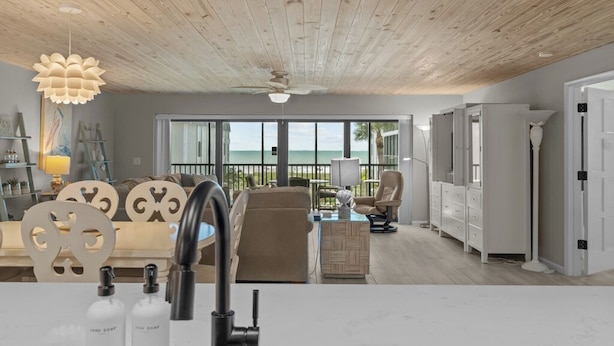 A modern living room with a view of the ocean, wooden ceiling, and a white sofa.