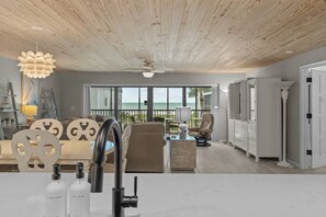 Un salon moderne avec vue sur l’océan, un plafond en bois et un canapé blanc.