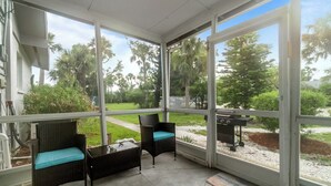 A covered patio area with wicker furniture and a grill.