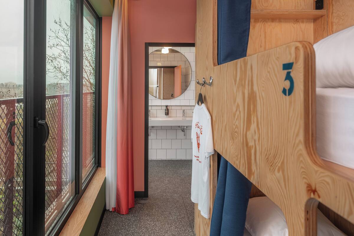 Une chambre d’hôtel avec un balcon, une armoire en bois portant un numéro, un miroir et une serviette blanche suspendue.