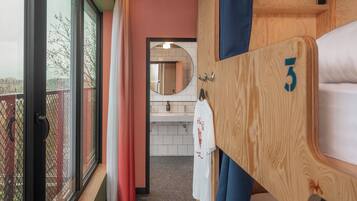 A hotel room with a balcony, a wooden wardrobe with a number, a mirror, and a white towel hanging.
