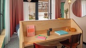 A modern room with a wooden desk, a chair, a book titled 'S E V G G I E X Y', a notebook, a mug, and a glass of orange juice. - Eklo Hotels Nantes City center - Île de Nantes (Nantes)