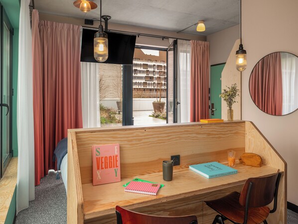 Una habitación moderna con un escritorio de madera, una silla, un libro titulado 'S E V G G I E X Y', un cuaderno, una taza y un vaso de jugo de naranja.