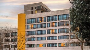 A multi-story building with a modern architectural design, featuring large windows and a prominent yellow cylindrical structure. - Eklo Hotels Nantes City center - Île de Nantes (Nantes)