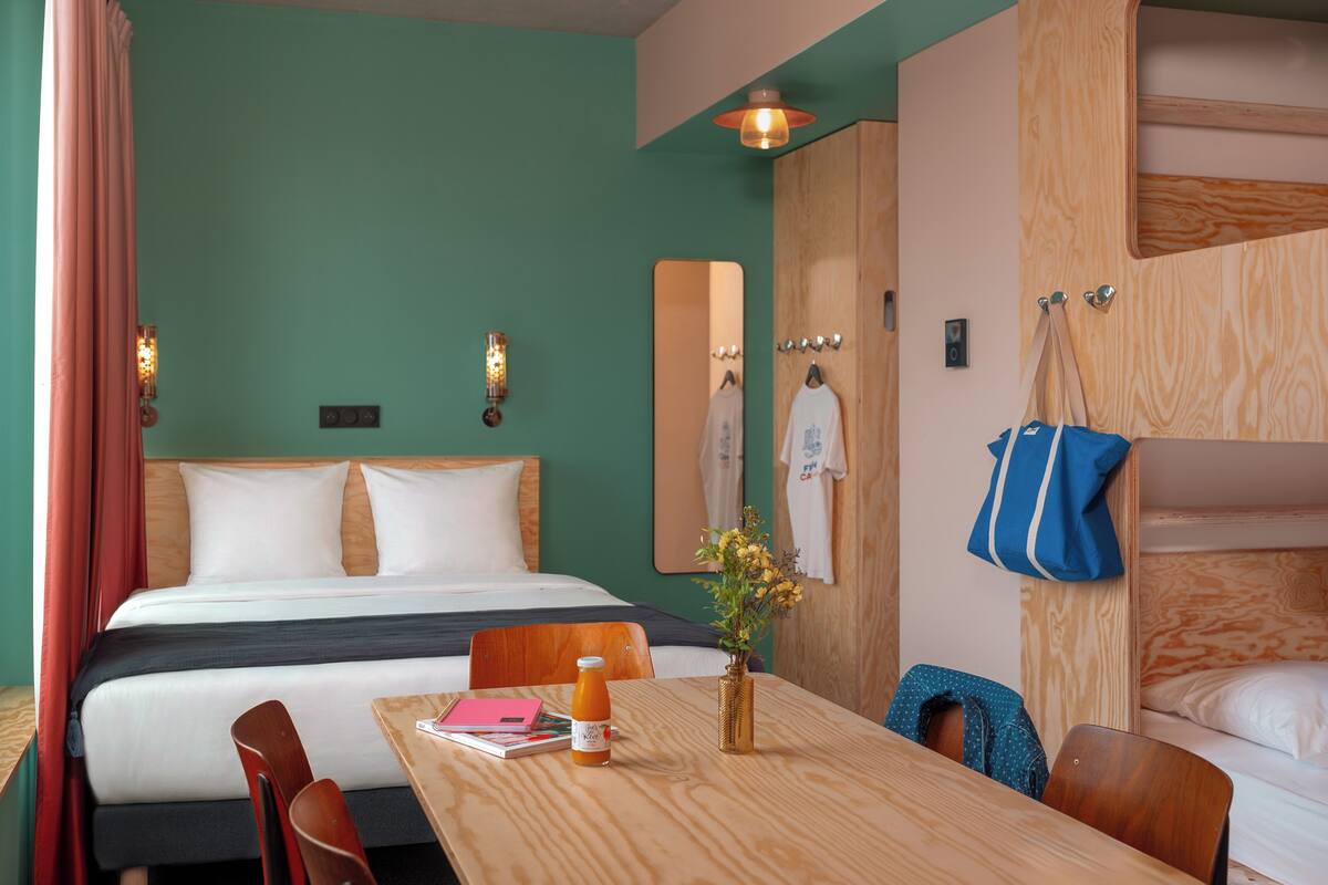 Une pièce comprenant un lit, une table en bois, une chaise, un miroir et un sac suspendu.