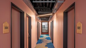 A hotel hallway with doors numbered 506 and 505, a patterned carpet, and a ceiling with exposed ductwork. - Eklo Hotels Nantes City center - Île de Nantes (Nantes)