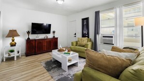 A modern living room with a flat-screen TV, a wooden cabinet, a green sofa, and a coffee table. - Pet-friendly Brickell Stay Near Beach & City (Miami)