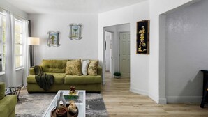 A living room with a green sofa, a coffee table with decorative items, and framed pictures on the wall. - Pet-friendly Brickell Stay Near Beach & City (Miami)