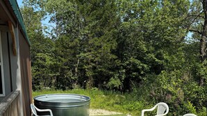 Une terrasse avec un jacuzzi, deux chaises en plastique blanches et une table en bois.