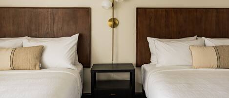 A hotel room with two beds, a nightstand with a lamp, and a checkered floor.