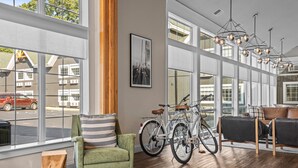 Ein geräumiger Raum mit großen Fenstern, einem grünen Sessel, einem Fahrrad und einer modernen Chandelier.