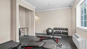 A gym with treadmills, benches, a ball, and dumbbells.