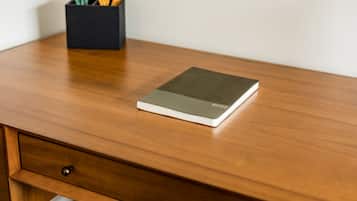 A wooden desk with a notebook and pencil holder.