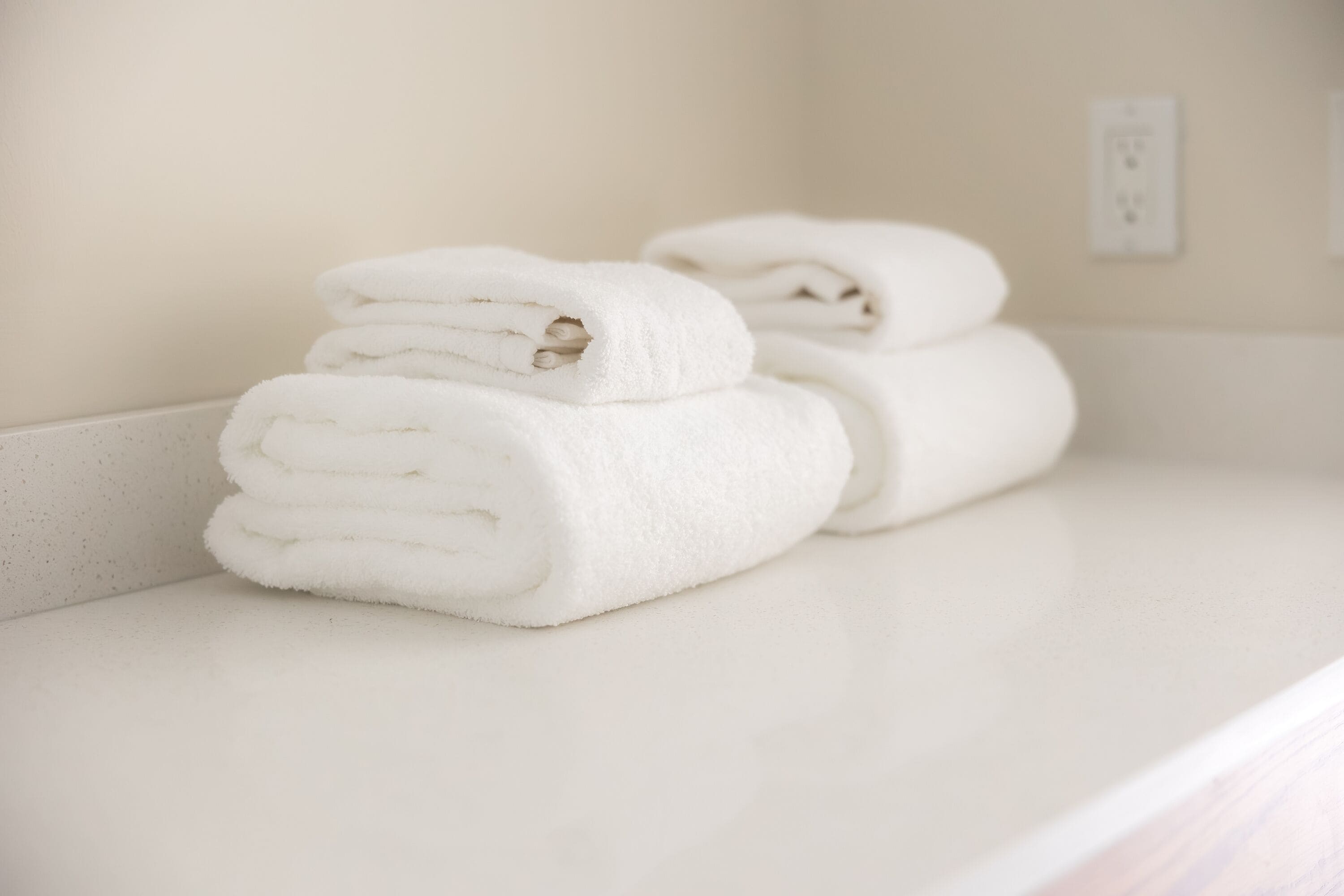 A stack of white towels on a white countertop.