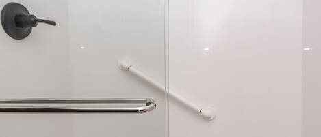 Een moderne douche met een glazen deur, een handgreep en een douchekop.