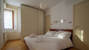 A bedroom with a bed, a wardrobe, a radiator, a window, and wall-mounted artwork.