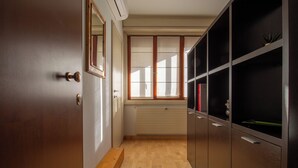 A hallway with a wooden floor, a radiator, and a door with a mirror.