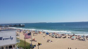 A beach with a pier, beach umbrellas, and a flag. - Beachfront Condo with Amazing Ocean Views  4th Fl (Old Orchard Beach)