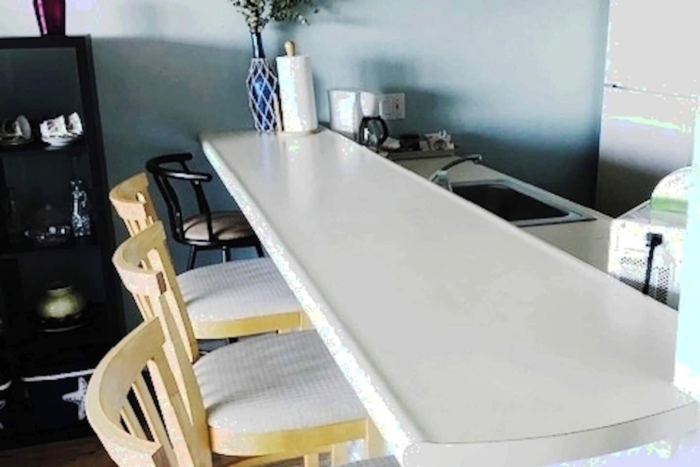 A long dining table with chairs, a vase with flowers, and a small cabinet with decorative items.