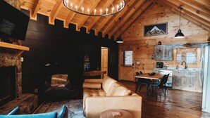 A cozy log cabin interior with a living room, dining area, and kitchen. - Amazing mountain view!5-star cabin,Modern,Minutes to BR&EJ,Hot tub,Games (Blue Ridge)