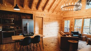 A wooden cabin interior with a kitchen, dining area, and seating space. - Amazing mountain view!5-star cabin,Modern,Minutes to BR&EJ,Hot tub,Games (Blue Ridge)