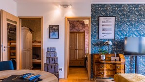 A room with a wooden dining table, a blue chair, a wooden cabinet with a plant, a framed poster on the wall, and a television. - Muggles welcome: Harz time-out in the Zauberquartier with sauna and swimming pool (Braunlage)