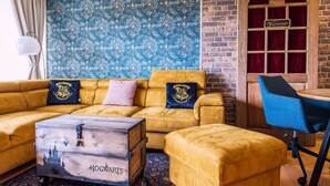 A room with a yellow sofa, a wooden chest, and a blue chair. - Muggles welcome: Harz time-out in the Zauberquartier with sauna and swimming pool (Braunlage)