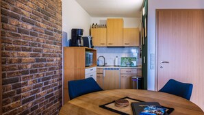 A compact kitchen with wooden cabinets, a microwave, and a coffee machine. There is a dining table with a book and a coaster. - Muggles welcome: Harz time-out in the Zauberquartier with sauna and swimming pool (Braunlage)