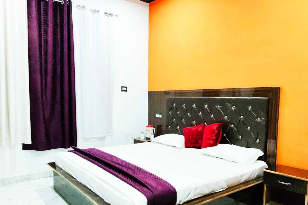 A modern hotel room with a large bed, a nightstand, and a wooden headboard.