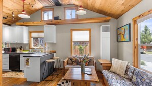 A cozy kitchen with wooden beams, a dining area with a wooden table, and a sofa with patterned cushions. - Walkable Urban Retreat. Remodeled 1920 Gem in Heart of Midtown-Walk to Breweries (Reno)