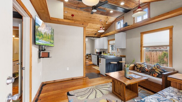 A modern interior with a wooden ceiling, a kitchen area, and a seating area with a sofa and a table. - Walkable Urban Retreat. Remodeled 1920 Gem in Heart of Midtown-Walk to Breweries (Reno)