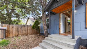 A modern house with a wooden deck, a tree, and a set of concrete steps leading to the entrance. - Walkable Urban Retreat. Remodeled 1920 Gem in Heart of Midtown-Walk to Breweries (Reno)