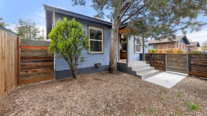 A modern house with a tree in the yard, a wooden fence, and a clear sky. - Walkable Urban Retreat. Remodeled 1920 Gem in Heart of Midtown-Walk to Breweries (Reno)