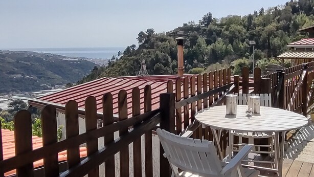 A wooden deck with a table and chairs, overlooking a scenic view of a valley and hills. - Bungalow Sixdays 3 with outdoor hot tub. (Camporosso)