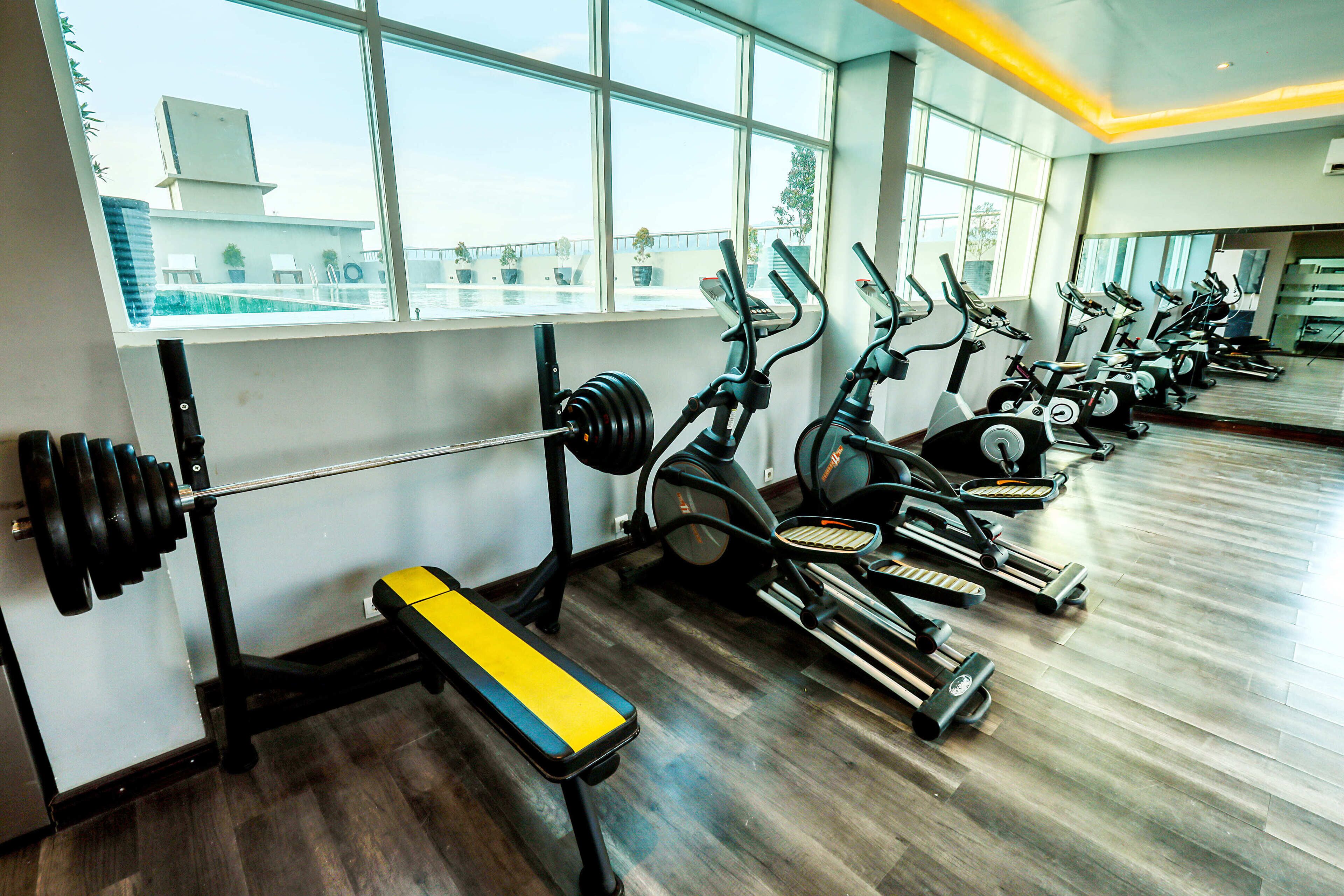 A gym with exercise equipment, a bench, and a weight rack.