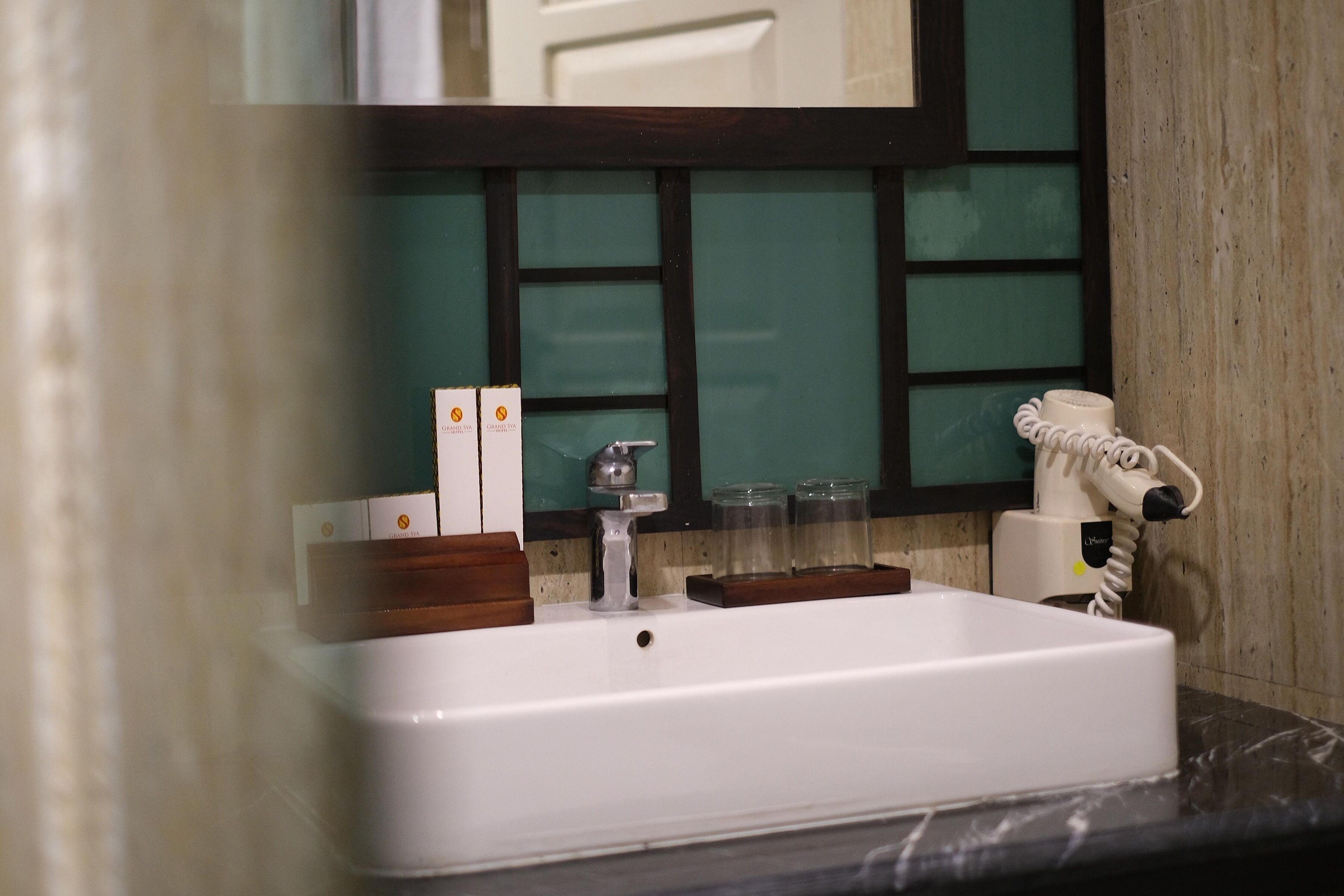 A bathroom with a white sink, a mirror, and a hairdryer on the countertop.