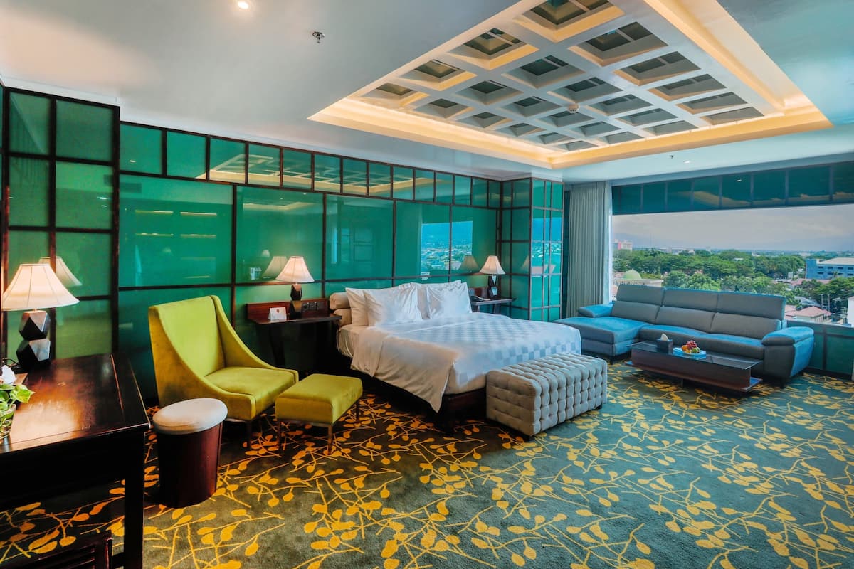Een hotelkamer met een bed, een slaapbank, een stoel, een bureau en uitzicht op de stad.