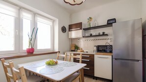 A modern kitchen with a dining table, chairs, a refrigerator, and a microwave. - ShortStayPoland Nowolipie B182 (Warsaw)