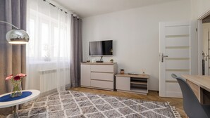 A modern living room with a TV, a small cabinet, a desk, and a chair. - ShortStayPoland Nowolipie B182 (Warsaw)