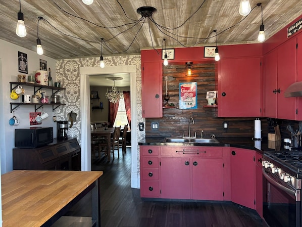 A kitchen with red cabinets, a wooden ceiling, and a chandelier.