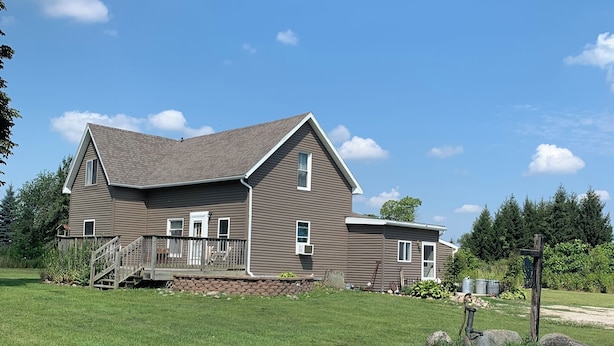 A two-story house with a front deck and a large front yard.