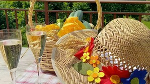 A table set with a plaid tablecloth, two glasses of champagne, a woven basket, and a decorative hat with felt flowers. - Surrounded by nature, cozy apartment with private garden and grill area (Novaledo)