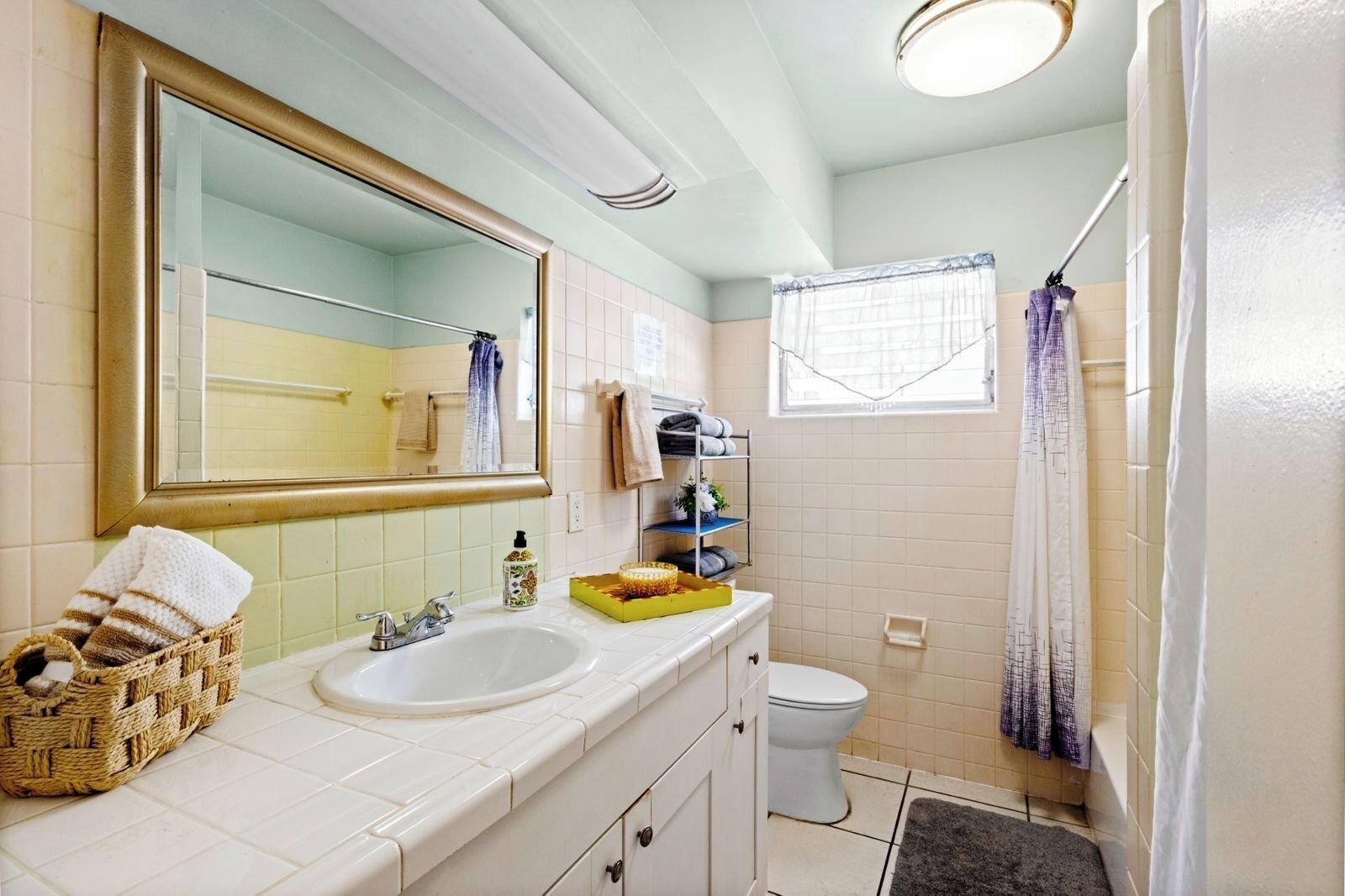 A bathroom with a white sink, a mirror, a toilet, and a shower area.