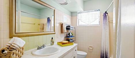 A bathroom with a white sink, a mirror, a toilet, and a shower area.