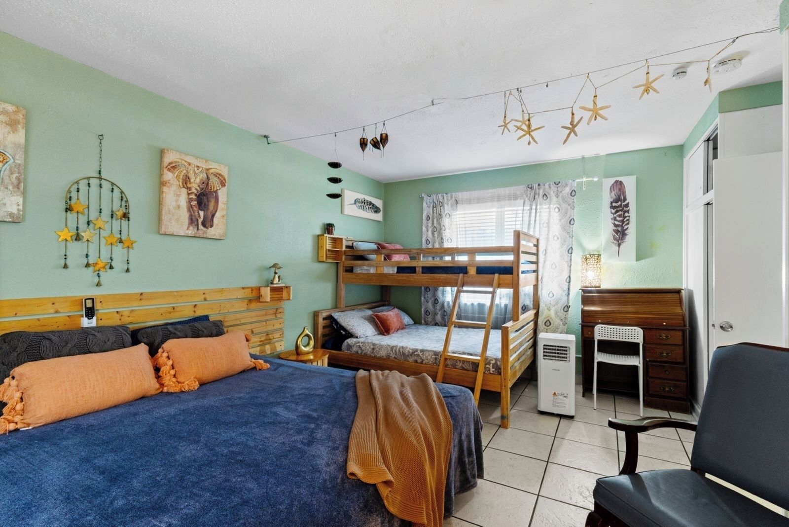 Una habitació de dormitori amb literes, escriptori, cadira i llit amb llençol blau.
